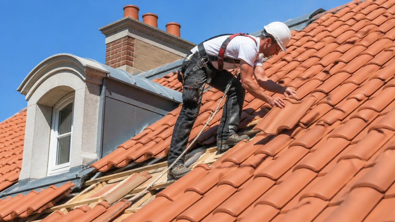 Couvreur posant des tuiles sur le toit d'une maison à Nancy